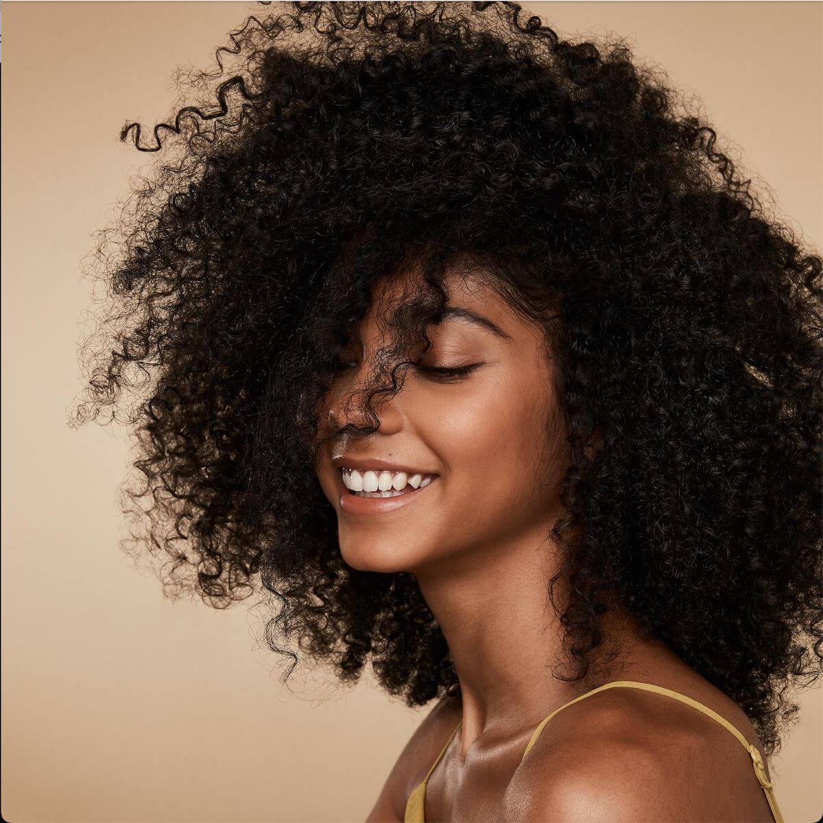 Beautiful woman with defined, natural curly hairstyle for low-maintenance styling.